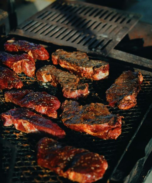 Sizzling steaks on a charcoal grill, perfect for a backyard BBQ.